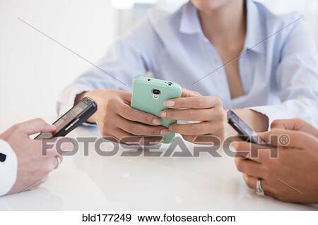 Business people using cell phones in office View Large Photo Image Stock Photo - Business people using cell phones in office. Fotosearch