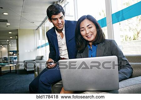Stock Photo - Business people using laptop in office. Fotosearch