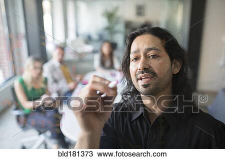 Businessman drawing graph on glass wall in office View Large Photo Image Stock Image - Businessman drawing graph on glass wall in office. Fotosearch