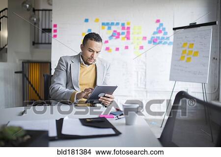 Picture - Businessman using digital tablet in office. Fotosearch