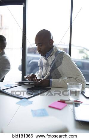 Stock Photograph - Businessman using digital tablet in office meeting. Fotosearch