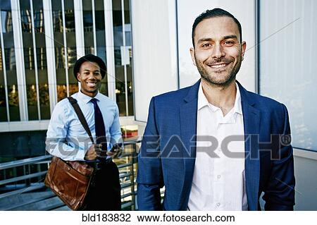 Stock Image - Businessmen smiling outside office building. Fotosearch