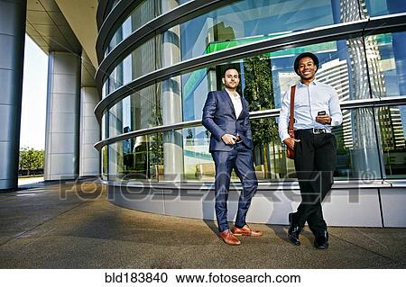 Stock Image - Businessmen smiling outside office building. Fotosearch