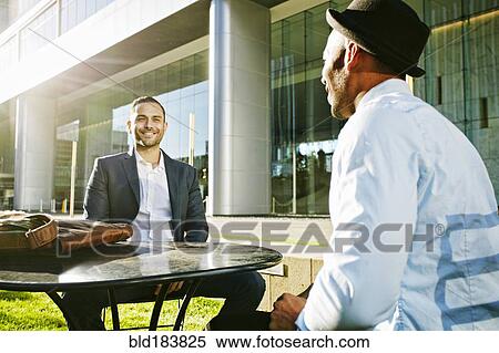 Stock Photography - Businessmen talking at table outdoors. Fotosearch