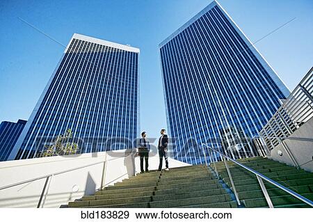 Stock Photo - Businessmen talking under highrise buildings. Fotosearch