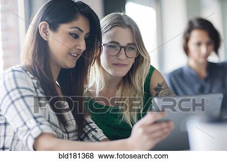 Stock Photo - Businesswomen using digital tablet in office. Fotosearch