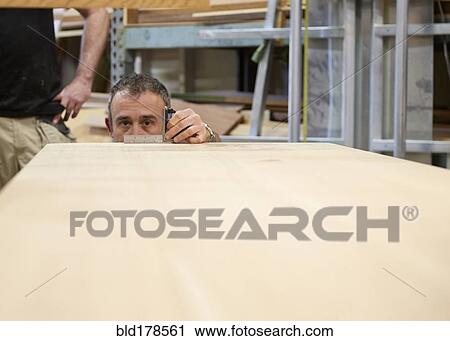 Carpenter measuring wood in workshop View Large Photo Image Stock Image - Carpenter measuring wood in workshop. Fotosearch