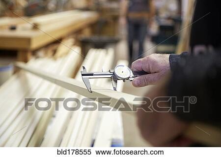 Stock Photography - Carpenter measuring wood in workshop. Fotosearch