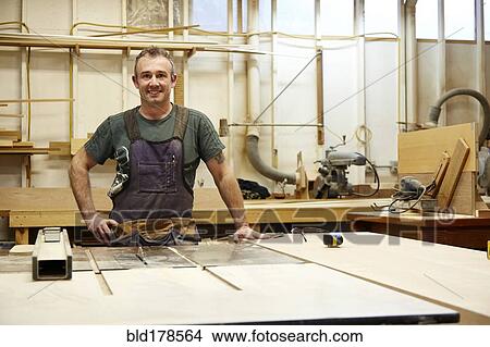 Picture - Carpenter smiling in workshop. Fotosearch