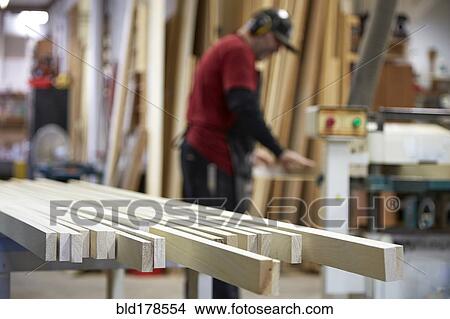 Picture - Carpenter using saw in workshop. Fotosearch