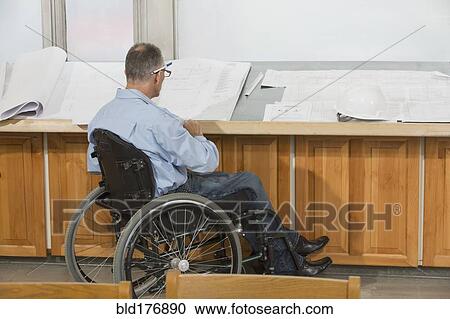 Stock Image - Caucasian architect in wheelchair talking in office. Fotosearch
