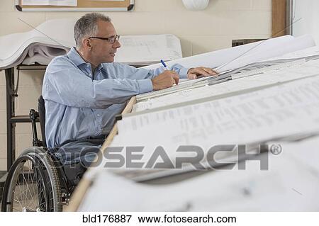 Stock Photo - Caucasian architect in wheelchair working in office. Fotosearch