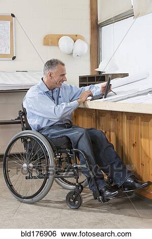 Stock Photograph - Caucasian architect using digital tablet in office. Fotosearch