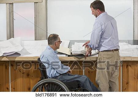 Stock Image - Caucasian architects talking in office. Fotosearch