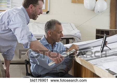 Stock Image - Caucasian architects talking in office. Fotosearch