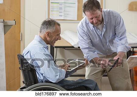 Stock Photo - Caucasian architects using digital tablets in office. Fotosearch