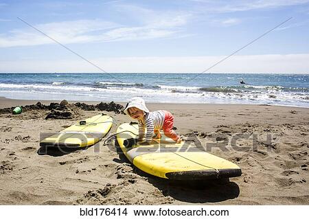 Picture - Caucasian baby crawling on surfboard. Fotosearch