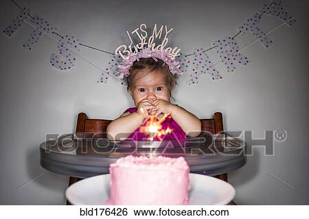 Stock Photograph - Caucasian baby girl admiring birthday cupcake. Fotosearch