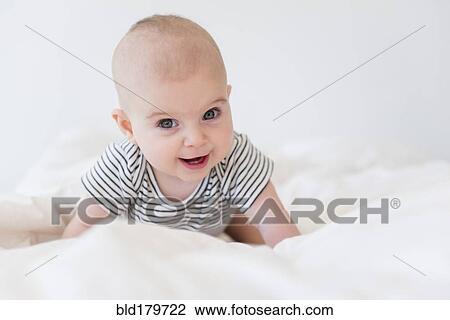 Stock Image - Caucasian baby girl crawling on bed. Fotosearch