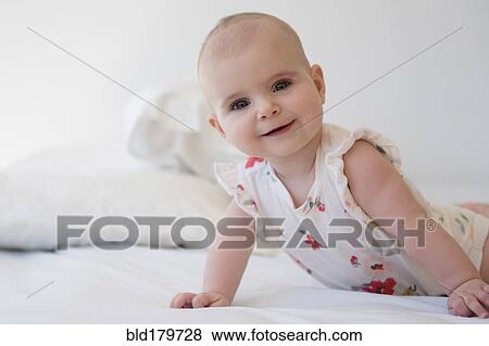 Stock Photo - Caucasian baby girl crawling on bed. Fotosearch