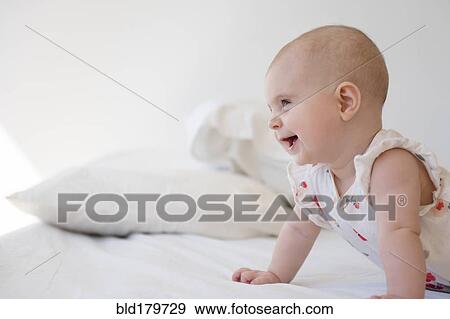 Stock Photo - Caucasian baby girl crawling on bed. Fotosearch