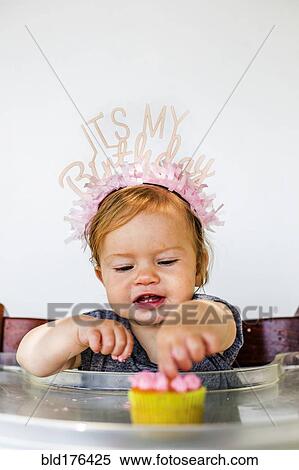 Stock Photography - Caucasian baby girl eating birthday cupcake. Fotosearch
