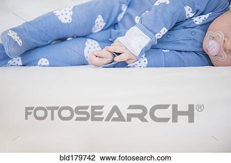 Stock Image - Caucasian baby girl laying on bed. Fotosearch