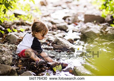 Stock Image - Caucasian baby girl playing in creek. Fotosearch