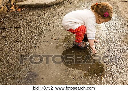Caucasian baby girl playing in puddle View Large Photo Image Stock Image - Caucasian baby girl playing in puddle. Fotosearch
