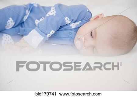 Stock Image - Caucasian baby girl sleeping on bed. Fotosearch