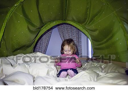 Picture - Caucasian baby girl using digital tablet in tent. Fotosearch