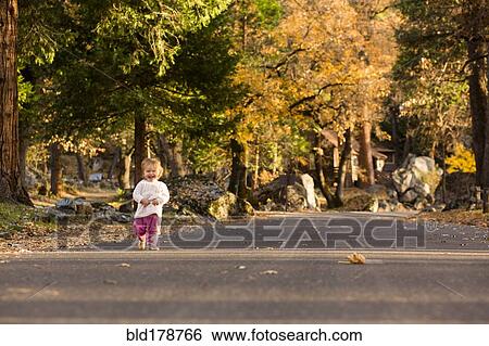 Stock Photograph - Caucasian baby girl walking on road. Fotosearch