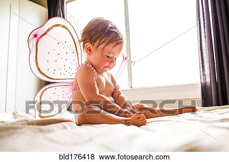 Stock Photo - Caucasian baby girl wearing fairy wings on bed. Fotosearch