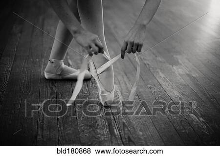 Stock Photo - Caucasian ballerina tying pointe shoes. Fotosearch