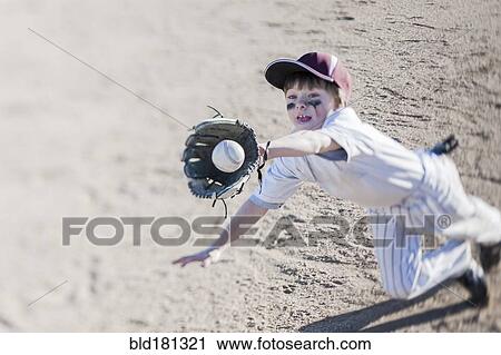 Stock Image - Caucasian boy catching baseball on field. Fotosearch