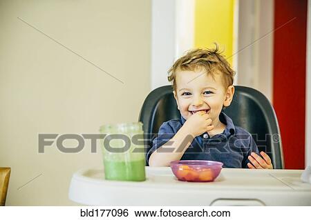 Stock Photograph - Caucasian boy eating in high chair. Fotosearch