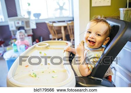 Stock Photograph - Caucasian boy eating in high chair. Fotosearch