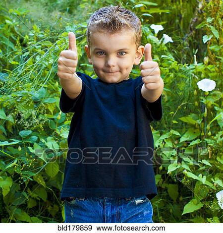 Stock Photo - Caucasian boy giving thumbs up in garden. Fotosearch