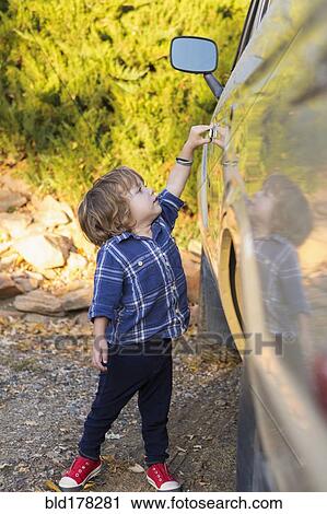 Stock Image - Caucasian boy opening car door. Fotosearch