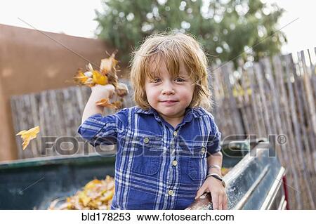 Stock Image - Caucasian boy playing in autumn leaves. Fotosearch
