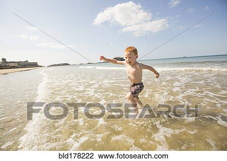 Caucasian boy playing in waves on beach View Large Photo Image Stock Image - Caucasian boy playing in waves on beach. Fotosearch