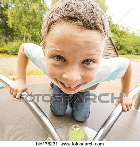 Stock Image - Caucasian boy playing on merry-go-round. Fotosearch