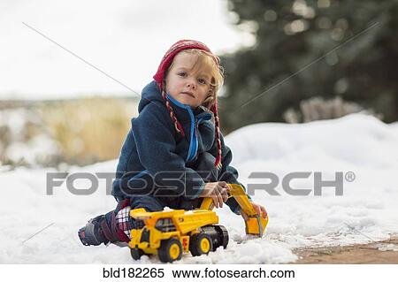 Stock Photography - Caucasian boy playing with truck in snow. Fotosearch