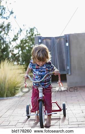 Caucasian boy riding tricycle in backyard View Large Photo Image Stock Image - Caucasian boy riding tricycle in backyard. Fotosearch