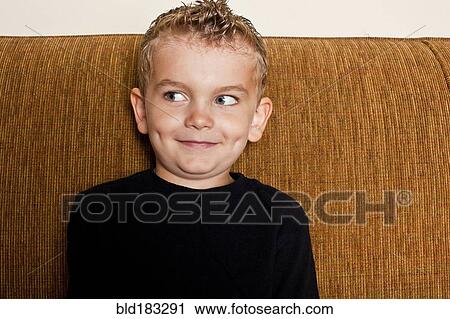 Stock Image - Caucasian boy sitting on sofa. Fotosearch