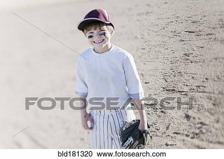Stock Image - Caucasian boy smiling on baseball field. Fotosearch
