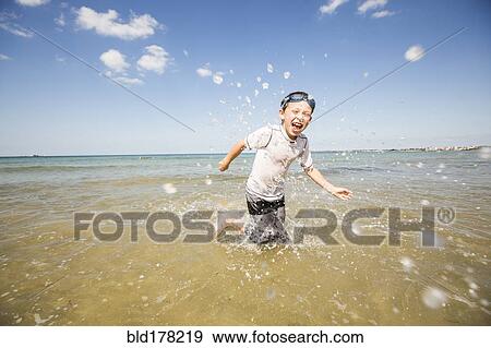 Caucasian boy splashing in waves on beach View Large Photo Image Stock Photo - Caucasian boy splashing in waves on beach. Fotosearch