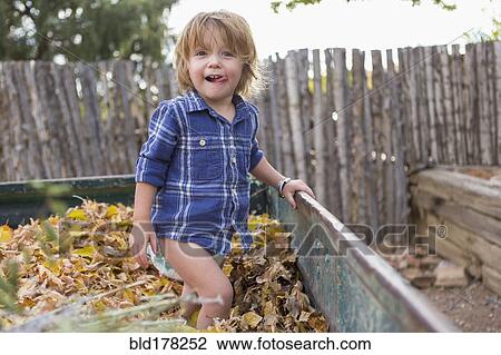 Stock Image - Caucasian boy standing in autumn leaves. Fotosearch