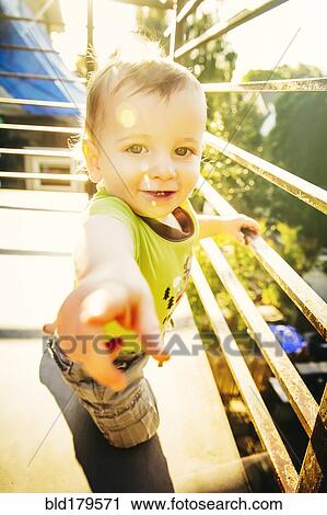 Stock Image - Caucasian boy standing on balcony. Fotosearch