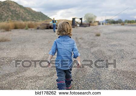 Stock Image - Caucasian boy walking in gravel. Fotosearch